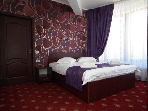 a bedroom with a bed with a purple wall at Vila Queen Mary in Constanţa