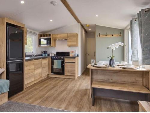 a kitchen with wooden cabinets and a black refrigerator at Cosy Caravan New for 2024! in Newquay