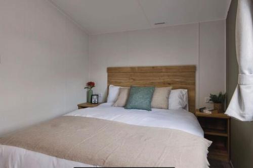 a bedroom with a large bed with a wooden headboard at Cosy Caravan New for 2024! in Newquay