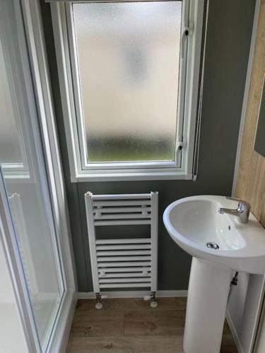 a bathroom with a sink and a window at Cosy Caravan New for 2024! in Newquay