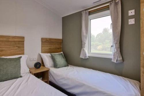 two beds in a room with a window at Cosy Caravan New for 2024! in Newquay