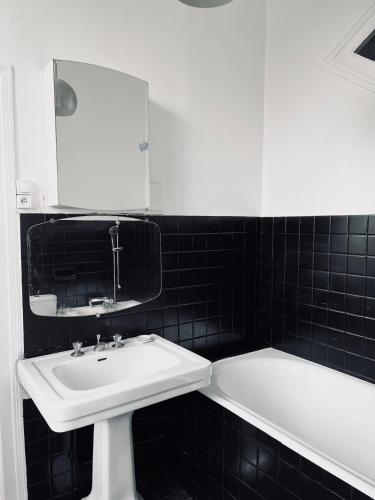 une salle de bain avec un lavabo, un miroir et une baignoire dans l'établissement Les Bons Amis, à Simard