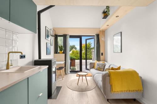 a kitchen and living room with a couch and a table at Romantisch huisje met houtkachel & airco op 2,5km van zee in Groede