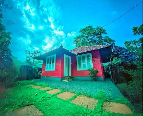 a small red house in the middle of a yard at The Stream View Villas Wayanad in Vythiri