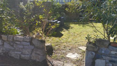 un jardin avec un mur en pierre et quelques plantes dans l'établissement Maison proche de l'océan, à Labenne
