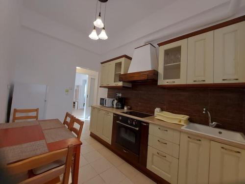 a kitchen with white cabinets and a table and a sink at Κατάλυμα στην πόλη Χαλάνδρι in Athens