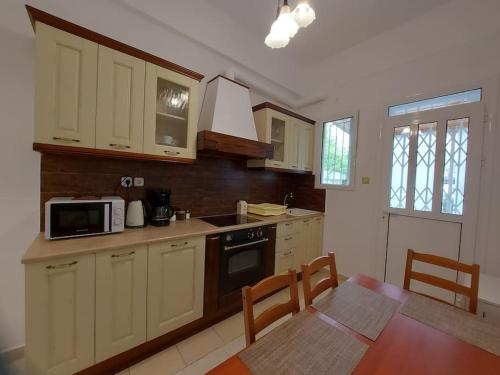 a kitchen with white cabinets and a table and a microwave at Κατάλυμα στην πόλη Χαλάνδρι in Athens