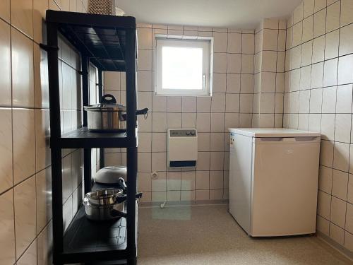 a kitchen with a shelf with pots and pans at Ferienwohnung Sonne & Sauna in Sönnebüll