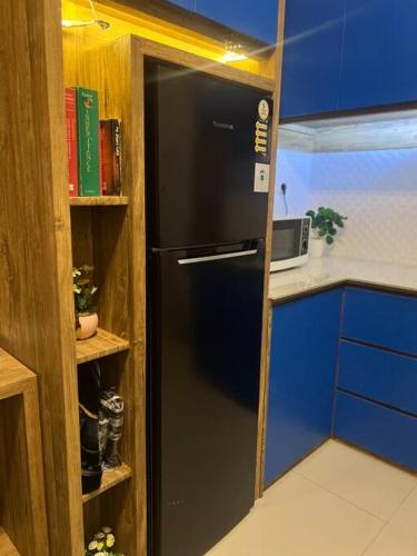 a black refrigerator in a kitchen next to a shelf at Luna Castle Parongpong @15 Minutes To Lembang/PVJ in Tutugan