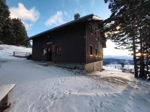 una cabaña en la nieve con huellas en la nieve en Črnuški dom na Mali planini en Krivčevo