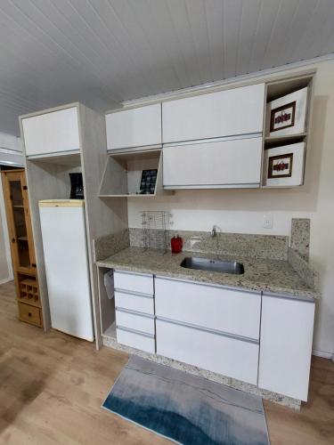 a kitchen with white cabinets and a refrigerator at Ap proximo ao lago in Bento Gonçalves