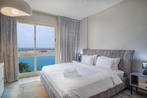 1 dormitorio con 1 cama grande y ventana grande en Water surrounded beautiful 2BR apartment, en Ras al Khaimah