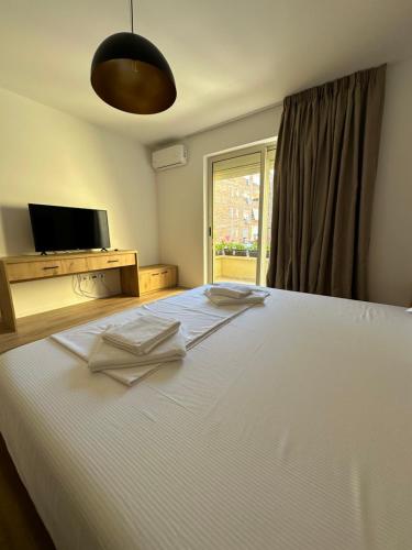 een slaapkamer met een groot wit bed en een raam bij New Bazaar Studios in Tirana
