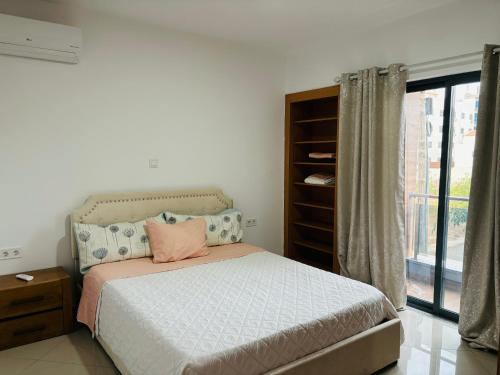 a bedroom with a bed and a window at Techas Near Beach Apt with Pool in Praia