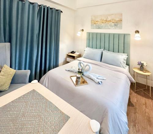 a bedroom with a large bed with blue curtains at Fully equipped Studio unit near Mactan Airport with WIFI, Pool & Gym Access in Mactan
