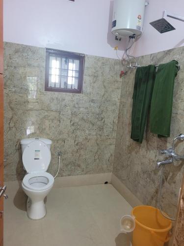 a bathroom with a toilet and a window and green towels at Most Spacious Stay in Shānti Niketan