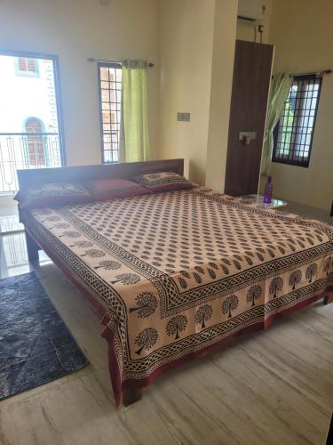 a large bed in a room with a bedspread on it at Most Spacious Stay in Shānti Niketan