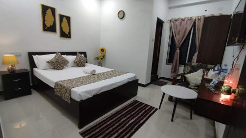 Un dormitorio con una cama y una mesa. en Hebron Haven, en Jaigaon