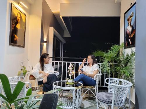 two women sitting on a balcony talking on their cell phones at Hebron Haven in Jaigaon