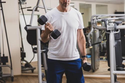 a man holding a dumbbell in a gym at Seehotel Jägerwirt in Turracher Hohe