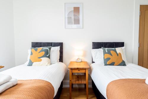 南安普敦的住宿－4-bed Retreat, Spacious Oasis With Modern Comfort，带2张单人床的带小桌子的房间