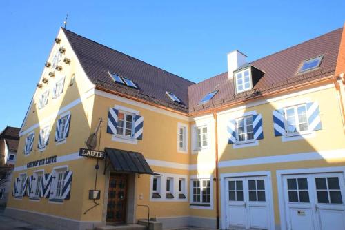 un grand bâtiment jaune avec un toit noir dans l'établissement Hotel und Gasthof Zur Laute, à Mindelheim