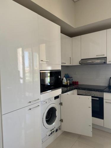 a kitchen with white cabinets and a washing machine at Amazing Apartment in Salalah