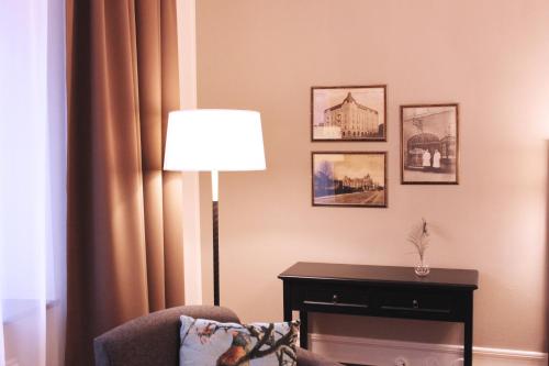 a room with a lamp and a chair and pictures at Home Hotel Drott in Karlstad