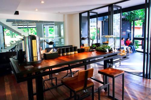 a kitchen with a large wooden table with chairs and windows at BED Changkian - Adults Only in Chiang Mai