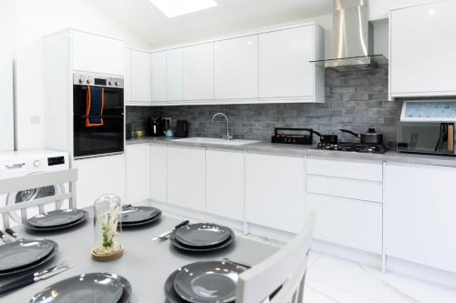 a white kitchen with white cabinets and black appliances at Albert Street Retreat, Windsor in Windsor