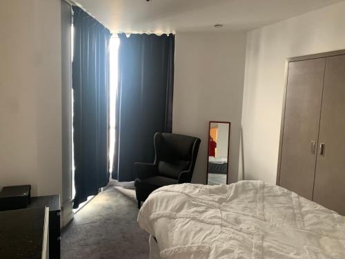 ロンドンにあるLuxury apartmentのベッドルーム1室(ベッド1台、黒い椅子付)