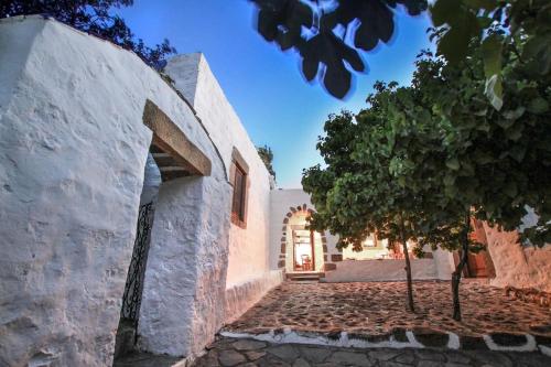 an entrance to a white building with a tree at Traditional Farm House Langada in Patmos