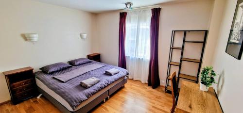 a bedroom with a bed with purple sheets and a window at Aurora Guesthouse in Grundarfjordur