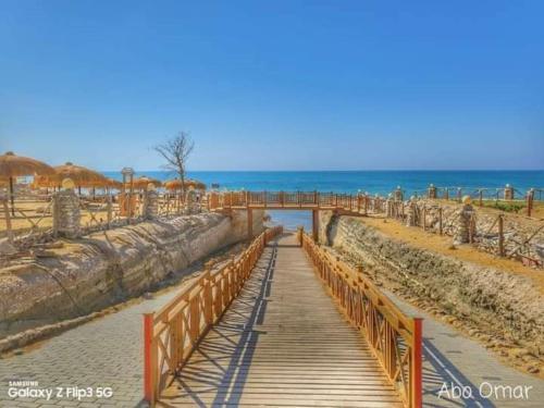 a wooden walkway on a beach with the ocean at TAVIRA Rass Suder"For Family" in Raʼs Matarma