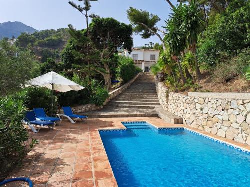 a swimming pool next to a stone wall and stairs at Villa Itaca in Mijas