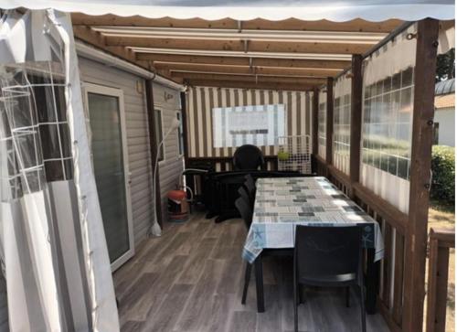 a screened in porch with a table and chairs at Détente et confort au Bois Dormant camping 4* MH240 in Saint-Jean-de-Monts