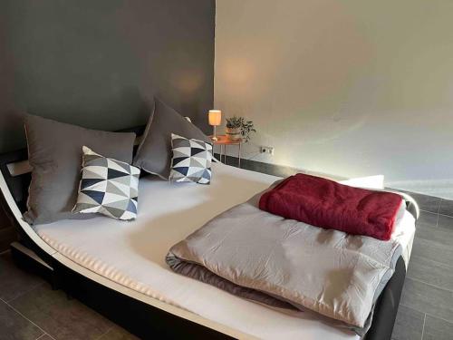 a bed with four pillows and a red blanket at Stilvolles Zimmer auf der Schwäbischen Alb in Sonnenbühl