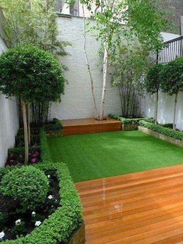 a garden with green grass and a wooden floor at Suit 3 cabin in Khujand