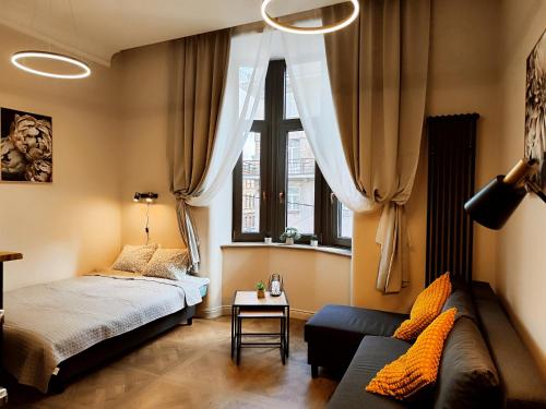 a bedroom with a bed and a couch and a window at New luxury apartment in the center in Rīga