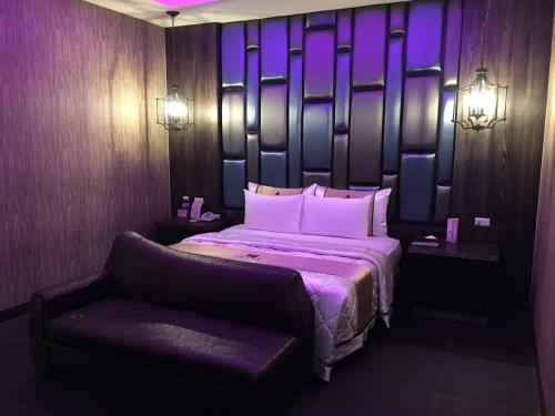 a bedroom with a bed and a chair and purple lighting at Ouwei Motel in Tainan