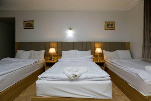 een slaapkamer met 2 bedden met witte lakens en 2 lampen bij Pyramids Express View Hotel in Caïro