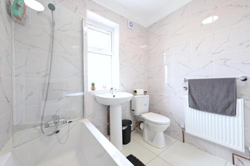 a white bathroom with a sink and a toilet at SPACIOUS 5 BEDROOM HOUSE NEXT TO TOTTENHAM STADIUM in London