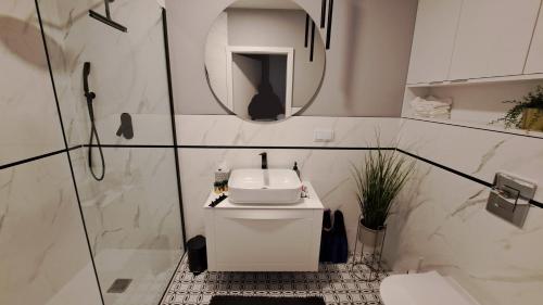 a white bathroom with a sink and a mirror at Apartament z widokiem Dziwnów & Spa, in Dziwnów