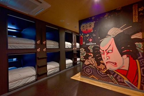 Zimmer mit Etagenbetten und einem Gemälde einer Frau in der Unterkunft Hotel Tomariya Ueno in Tokio
