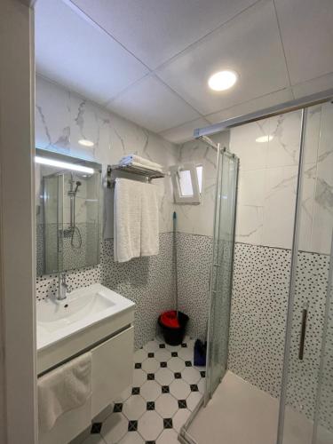 un bagno con doccia, lavandino e porta doccia in vetro di Aparthotel Pelicano a Benidorm