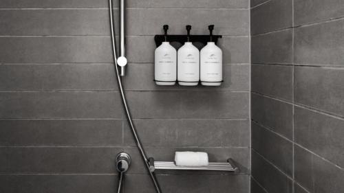a shower with three white bottles on a wall at Airport Bed and Breakfast in Cancún