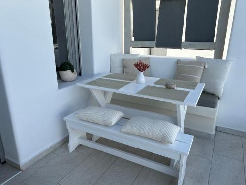 a white table and bench with pillows on a porch at Thiramor houses in Mesaria