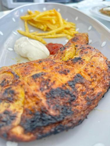 a plate with a piece of food and french fries at Maison des Oliviers, Yasmine Hammamet, Bouficha in Hammamet Sud