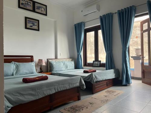 um quarto com 2 camas e uma janela com cortinas azuis em Tulip Mui Ne em Phan Thiet