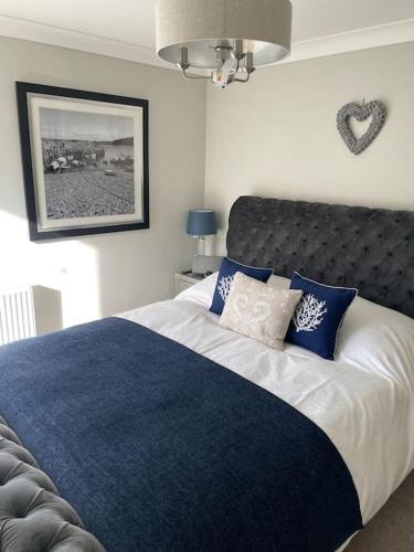 a bedroom with a large bed with blue and white pillows at Seaside Modern Apartment in Westward Ho